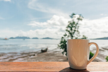 Morning coffee mug with low tide sea view as background.