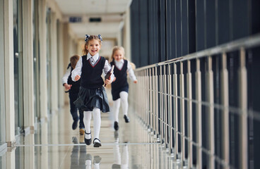 Active school kids in uniform running together in corridor. Conception of education