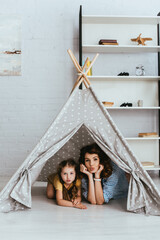 cute child and young nanny making duck faces and looking at camera while lying in kids wigwam © LIGHTFIELD STUDIOS