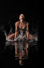 sexy girl splashes in the water. background is black