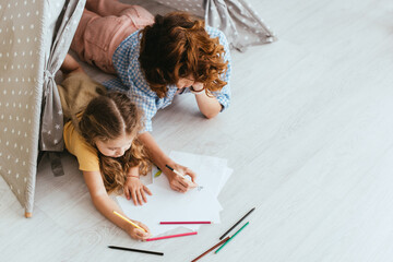 high angle view of nanny and child drawing while lying in toy wigwam © LIGHTFIELD STUDIOS