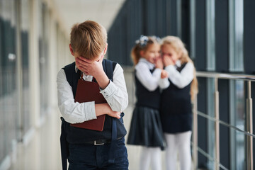 Little boy gets bullied. Conception of harassment. School kids in uniform together in corridor