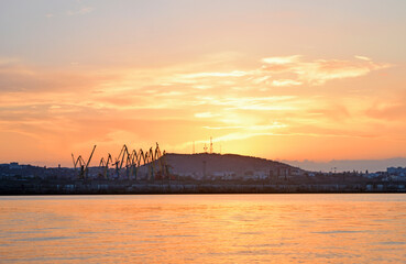 View of silhouettes of cranes and a hill against the sky