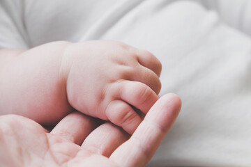 Tiny baby hand holding mother's finger. New life, togetherness and love concept.