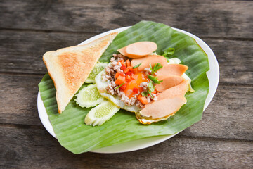 Fried eggs with sausage cucumber pork and bread for breakfast on banana leaf background - Pan Fried Egg with Toppings