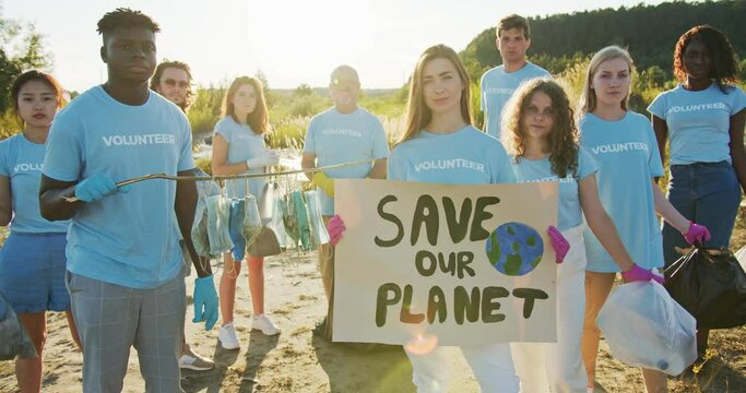 Group of multiethnic volunteer protesting against environmental pollution. Enthusiastic eco activists with a poster Save Our Planet and trash bags looking at camera. Ecology, nature saving concept.