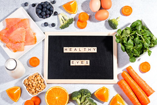 Foods That Help Maintain Eyes Healthy, Supplements For Keeping Good Vision, Vitamins For Eyes. Assortment Of Food For Eye Health On Concrete Background, Flat Lay, Top View