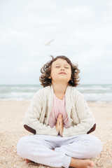 Fototapeta na wymiar little girl meditating on the beach