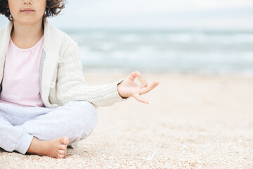 little girl meditating on the beach - obrazy, fototapety, plakaty