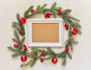 Christmas light background, fir branches wreath with red baubles and berries, beautiful frame and copy space for your text. White creative layout, flat lay, top view.