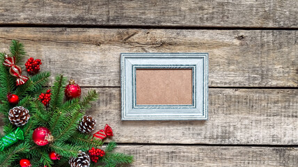 Christmas wood grunge background and frame for wishes. Top view, fir twigs, berries, baubles. Christmas, New Year decoration, pine tree branches and cones, light background, flat lay, copy space.