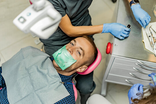 Patient with a kofferdam is being treated by a dentist.Dentist performs dental treatment by putting an injection to a smiling patient.