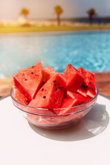 Round plate with watermelons near the pool on the plank floor. Summer concept. 