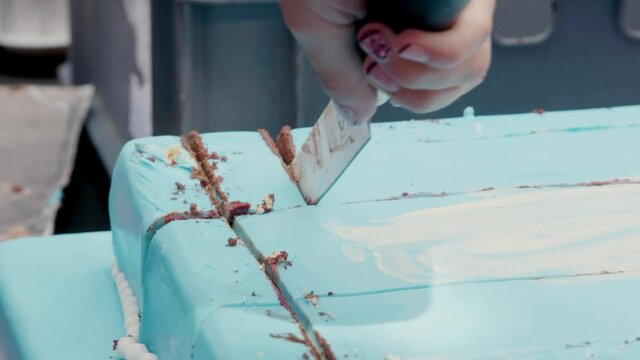 Cutting a chocolate celebration cake. Blue marzipan cover