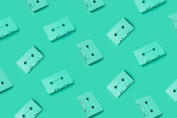 Green cassette tapes overload. Retro cassette tapes pattern on a green background. Minimalist art photography, creative art photography. Music tapes placed on a monochrome background pattern.
