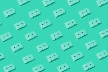 Green cassette tapes overload. Retro cassette tapes pattern on a green background. Minimalist art photography, creative art photography. Music tapes placed on a monochrome background pattern.