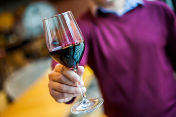 Closeup of young man holding a glass of red wine.