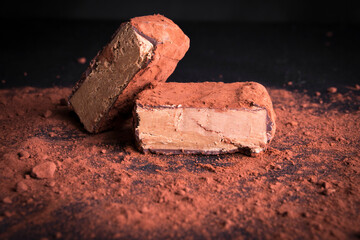 cocoa pave photographed in the studio, with cocoa powder decorating the photograph. On a black background, ideal for backgrounds, advertising and decoration of spaces.
