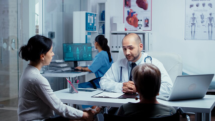 Elderly retired handicapped woman at doctors appointment with her daughter. Dsabled disability handicapped old person treatment in modern private hospital or clinic. Medicine and health care system