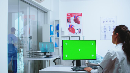 Nurse in blue uniform leaving hospital cabinet and doctor using computer with replaceable display. Computer with repleceable screen used by medicine specialist in hospital and wearing uniform.