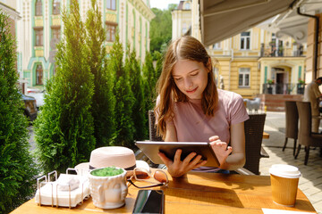 young woman using tablet pc in a cafe on a summer terrace