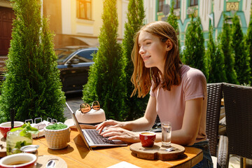 young woman using laptop in a cafe on a summer terrace