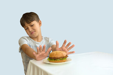 young boy held out his hands, palms open. refuses a hamburger