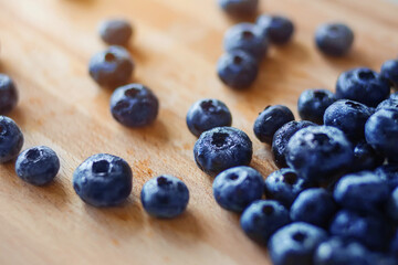 On the kitchen wooden board lie large ripe washed berries of forest blueberries, illuminated by sunlight. Rich harvest.
