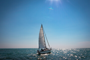 Naklejka premium sailboat on the sea with the sun barely in view