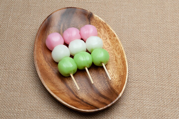 Japanese traditional sweet called Dango Mochi on wooden platter. Isolated on jute background. Close-up. Top view. Copy space.