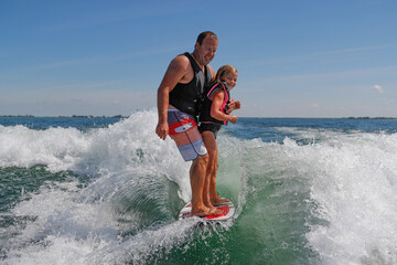 Fototapeta premium Man and young girl surfing together.