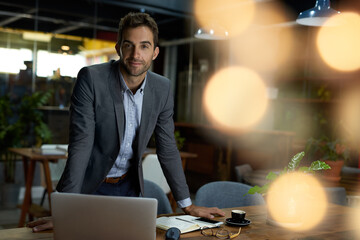 Businessman leaning on his desk in an office after hours - obrazy, fototapety, plakaty