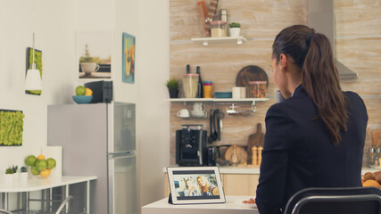 Business woman during a video call with sister while eating breakfast. Using modern online internet web technology to chat via webcam videoconference app with relatives, family, friends and coworkers