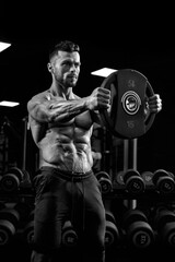 Fototapeta na wymiar Portrait of bodybuilder holding weights straight out.