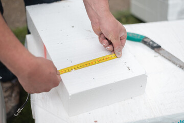 Construction worker measuring styrofoam with measuring tape