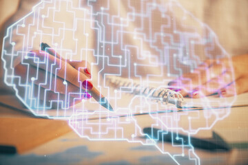 Double exposure of woman's writing hand on background with brain hologram. Concept of brainstorming.