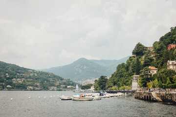 Lake Como view from Como сity promenade on a cloudy day. Boats and yacht on the water