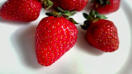 Strawberries on a white plate and white plate. Selective focus