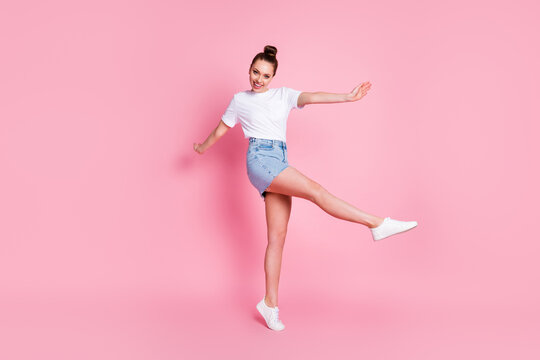 Full size photo of enthusiastic candid girl enjoy rejoice rest relax raise leg wear good look outfit gumshoes isolated over pink color background
