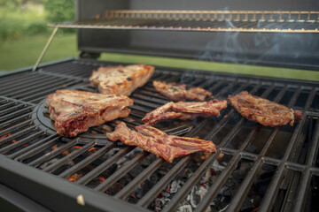 Home barbecue with charcoal in the backyard grilling steaks and other meats for carnivore diet.