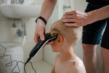 Obraz na płótnie Canvas Father making haircut for son at home