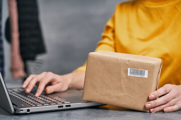 Woman sending parcel using her laptop. Working from home