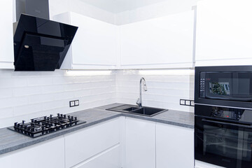 interior of white furniture of a compact kitchen, glossy cabinets with built-in household appliances.