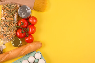 Top view on food donations on green background with copyspace - pasta, fresh vegatables, canned food, baguette, eggs, organic oil. Donation and contactless delivery food concept