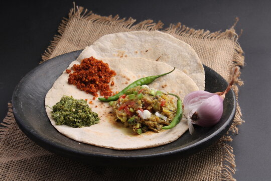 Baigan/Baingan Bharta - Mashed roasted Eggplant cooked with spices & vegetables, crushed gree chillis - thecha and garlic chutney. Served with Jowar flour flat bread known as bhakar/bhakri.