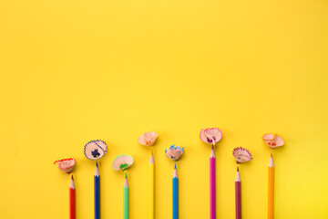 Color pencils and shavings on bright yellow background with copyspace for text, leaflet. Back to school or training courses concept, selective focus