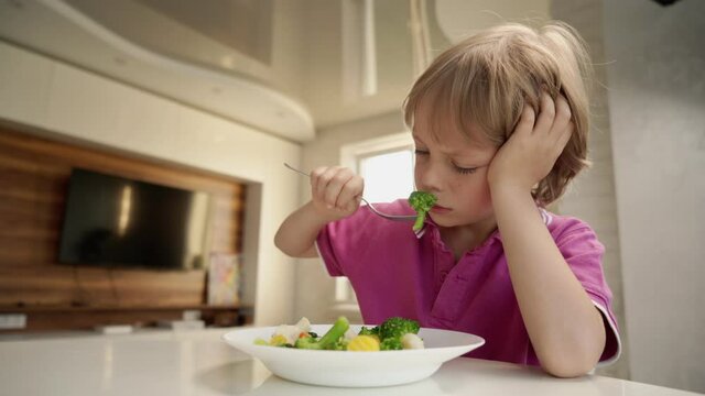 Boy tries to eat a vegetables but dosen't like it and rejects the food. Healthy food concept. Children and vegetables