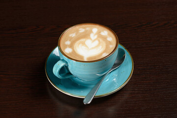 Cup of latte coffee on a wooden table with a teaspoon. Photos for restaurant, cafe and bar menus