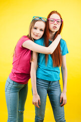 lifestyle people concept: two pretty young school teenage girls having fun happy smiling on yellow background wearing glasses