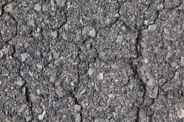Spękana asfaltowa nawierzchnia drogi.